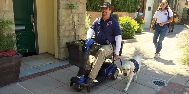 Handicapé sur un fauteuil roulant avec son chien dans la rue