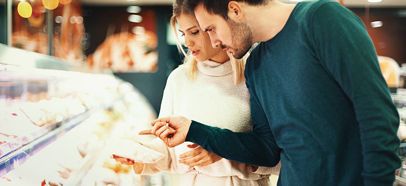 Couple devant un rayon de viande dans un supermarché