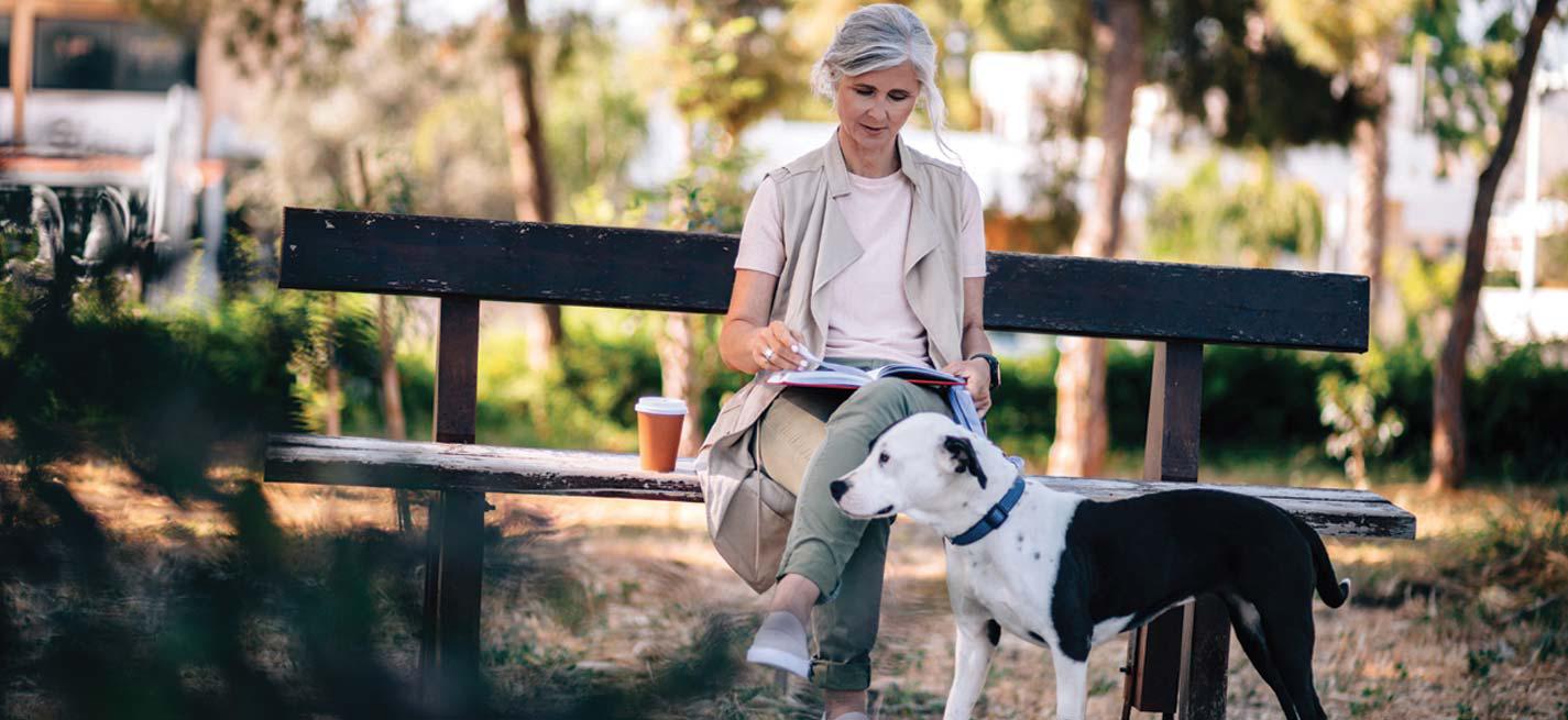 Une dame assise sur un banc dans un parc avec son chien